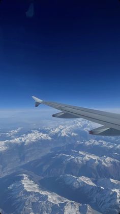 the wing of an airplane flying over snow covered mountains