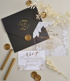 the wedding stationery is laid out on top of some gold and black paper with wax stamping