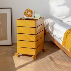 a yellow dresser next to a bed in a room with hardwood floors and white walls