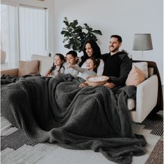 a family sitting on a couch under a blanket