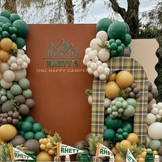 an outdoor party with balloons and greenery on the front entrance to robertson's one happy camper