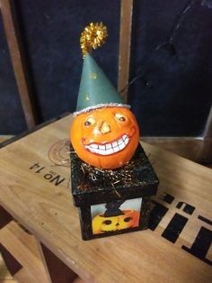 a pumpkin with a party hat on top of it's head sitting on a box