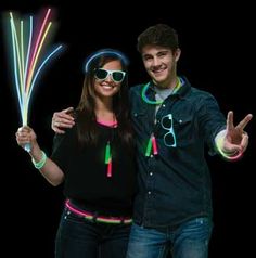 a man and woman are posing for a photo with glow sticks in their hands while wearing sunglasses