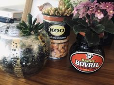 some plants are sitting on a table next to two jars with food in them and one is empty