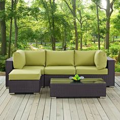 a couch and table on a deck with trees in the backgroung area