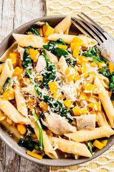 pasta with chicken, spinach and cheese in a white bowl on a wooden table