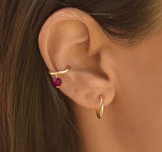 a close up of a woman's ear with a red stone in the middle