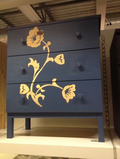 a blue dresser with yellow flowers painted on the front and sides, in a store