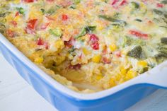 a casserole dish with vegetables and cheese in it sitting on a white table