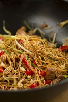 stir fried noodles with meat and vegetables in a wok