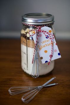 there is a jar with some cookies in it and two whisks next to it