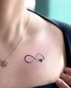 a woman's chest with an infinite symbol tattoo on her left shoulder and heart in the middle