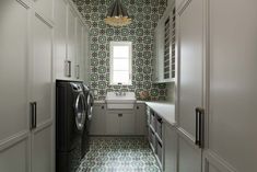 a washer and dryer in a small room with patterned wall paper on the walls