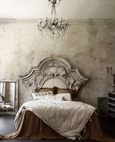 a bedroom with an ornate headboard and chandelier hanging from it's ceiling