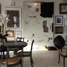 a dining room table with chairs and pictures on the wall