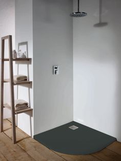 a bathroom with white walls and wooden flooring next to a shelf filled with towels