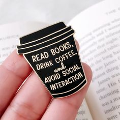 a hand holding a coffee cup pin with the words read books drink coffee and avoid social interaction