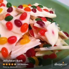 a green bowl filled with lots of gummy bears in white frosting and jelly beans