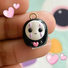 a small black and white panda bear charm with pink hearts on it's back