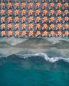 an aerial view of beach chairs and umbrellas on the sand next to the ocean