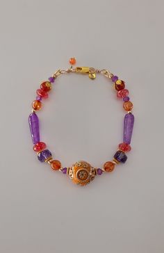 "\"One Thousand and One Night\" bracelet. Amethyst teardrop and roundel beads, dark pink and orange tourmaline and a big Indonesian orange clay bead at the center with rhinestones and golden color ornaments. 18K gold filled clasp, beads and roundels between.  Violet, orange, sunny, warm tones and a touch of mystery coming from the East for this colorful, bright bracelet.    Length:  18,5cm -20cm You will receive it in a gift package." Color Ornaments, Pink Gemstone Bracelet, One Thousand, Clay Bead, Gift Package, Pink Gemstones, Golden Color, Clay Beads, Gemstone Bracelet