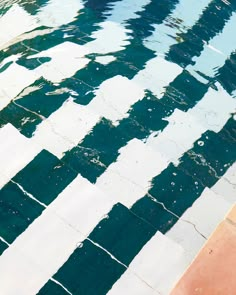 an umbrella is sitting on the edge of a pool that has been painted green and white