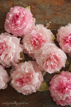 some pink flowers are on a wooden surface