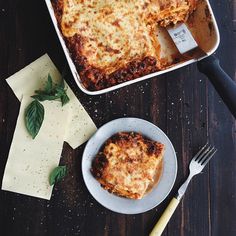 a casserole dish with meat and cheese in it on a wooden table next to a fork