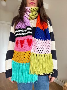 a woman wearing a multicolored knit scarf with hearts on the front and sides