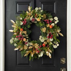 a christmas wreath on the front door with berries and greenery hanging from it's side