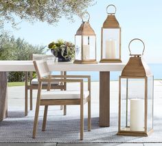 an outdoor dining table with two lanterns on it and some chairs around the table,