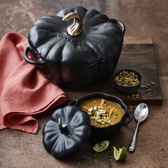 pumpkin soup in a black pot and two bowls with spoons