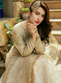 a woman sitting on the steps wearing a white and gold dress with an intricate head piece