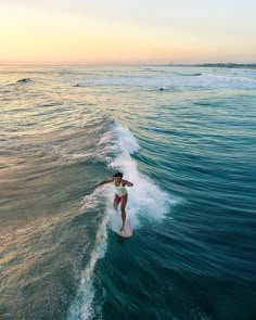 a person riding a surfboard on a wave in the ocean at sunset or dawn