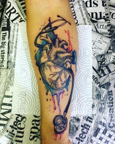 a heart and arrow tattoo on the right leg, with watercolor splashs all over it