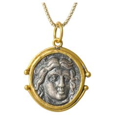 a gold and silver medallion with a woman's face in the center on a chain