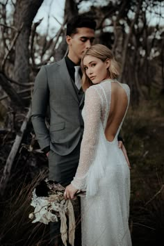 a man and woman standing next to each other in the woods