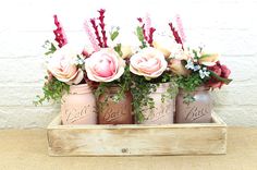 four jars with flowers in them sitting on a table