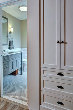 an open door leading to a bathroom with white cabinets