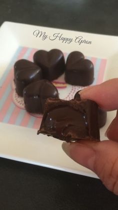 a hand holding a piece of chocolate on top of a plate