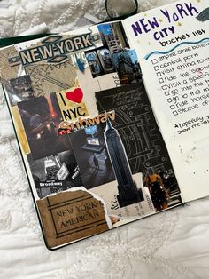 an open new york city notebook with pictures and words on the pages, sitting on top of a bed