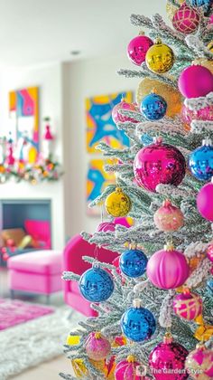 a brightly colored christmas tree in a living room with pink furniture and colorful ornaments on it