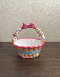 a small basket that is sitting on top of a wooden table with a bow tie around the handle