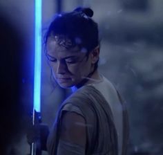 a woman holding a light saber in the dark knight film star wars, looking down at her face