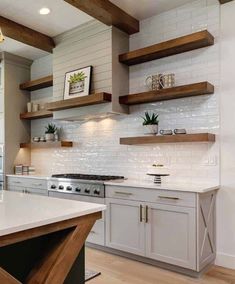 a kitchen with white cabinets and wooden shelves on the wall, along with an island countertop