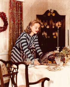 an old black and white photo of a woman setting a table with a turkey on it