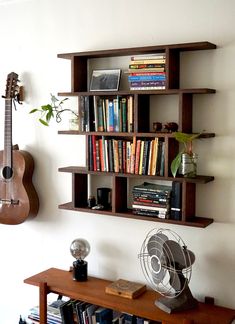 a book shelf with books and a guitar on it