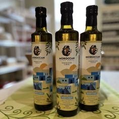 three bottles of extra virgin olive oil sitting on top of a cloth covered tablecloth