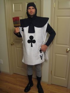 a man dressed in a costume holding a book and wearing a hat with an ace playing card on it