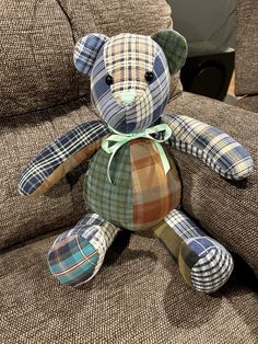 a plaid teddy bear sitting on top of a brown couch next to a pillow and chair